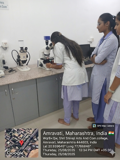 Students observing live microbial samples under phase contrast microscope.